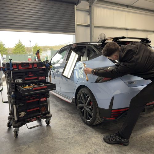 Paintless Dent Repair specialist repairing a dent on a customers vehicle in our South Wales workshop